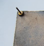 Rückseitig an einer Schrifttafel angegossene Nocken zur Anbringung einer Bronzetafel an einer Wand oder auf einem Sockel